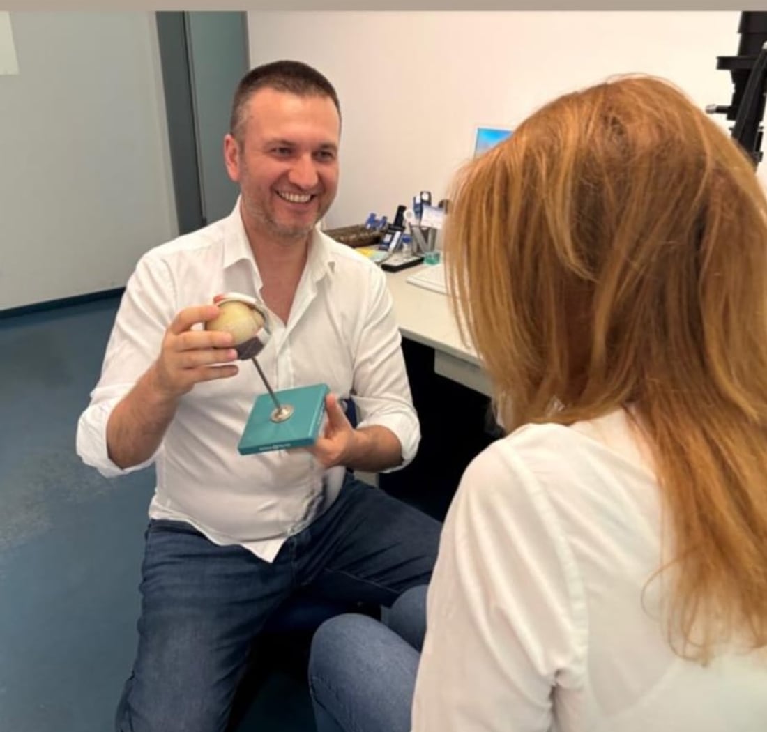 Svetlin Hristov erklärt einer Patientin ein anatomisches Augenmodell in der Praxis